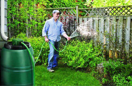 De bedden water geven met opgevangen regenwater